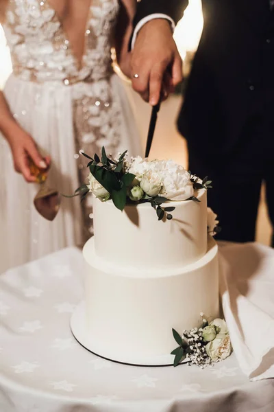 Midsection of bride and groom cut and serving wedding cake