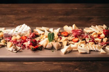 Ahşap tahtaüzerinde çeşitli peynir ve çilek çeşitleri