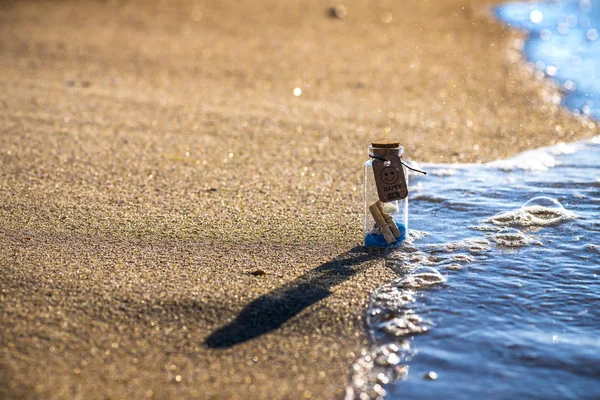 Piccola bottiglia felice su sabbia e mare vacanza onda — Foto Stock