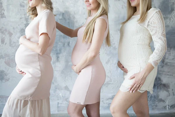 Tres mujeres embarazadas de pie una detrás de la otra en vestidos ligeros Fotos De Stock
