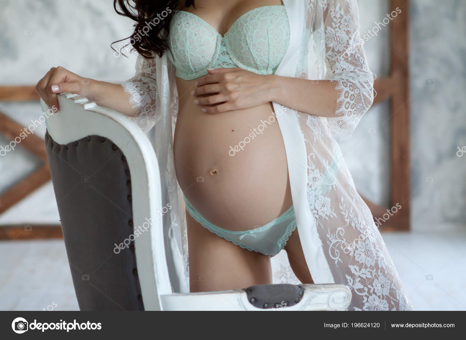 Pregnant woman in a beautiful white peignoir and lingerie Stock