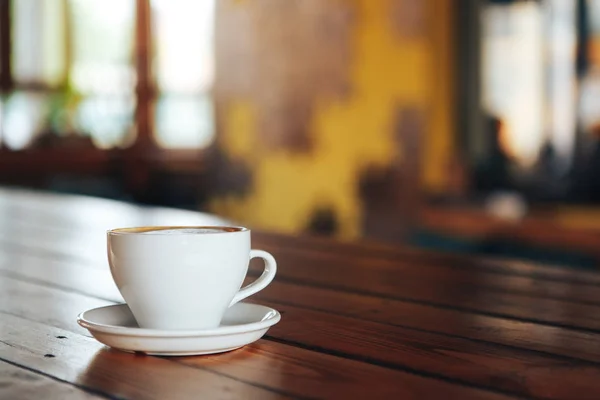 在木桌上的白色杯子里的热咖啡。咖啡厅里一张木桌上的一杯白咖啡。早上在咖啡馆里喝一杯陶瓷白咖啡 — 图库照片