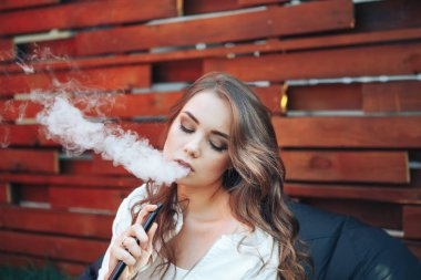 Genç kadın bir nargile açık havada sigara. Sigara zevk. Sigara genç bir kadın portresi. Arka plan bir ahşap duvar