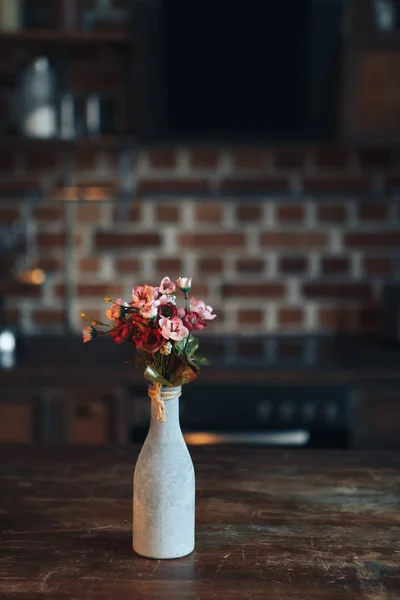Цветы в вазе стоят на кухонном деревянном столе — стоковое фото