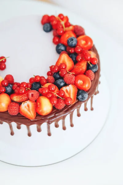 Gâteau à la crème de fromage blanc, décoré de ganache et de baies rouges sur un stand blanc — Photo