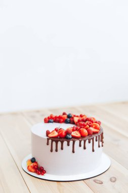 Beyaz peynirli kremalı pasta ganache ve kırmızı meyveler beyaz bir stand ile dekore edilmiş