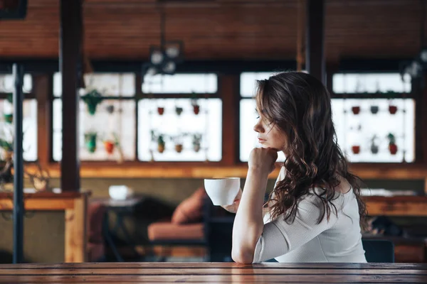 Молодая женщина в кафе с чашкой кофе смотрит в меню — стоковое фото