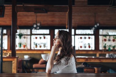 Genç kadın bir fincan kahve ile bir kafede menüye görünüyor