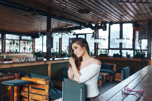 Young woman with long hair sitting at a bar stool in a cafe — Stock Photo, Image