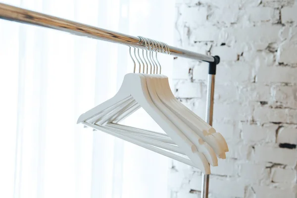 White empty hangers against a white brick wall background — Stock Photo, Image