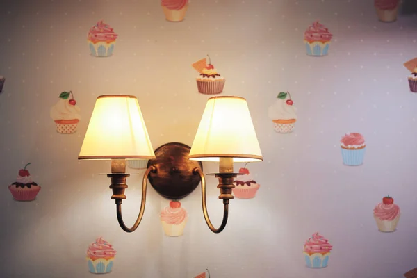 Настенная лампа в детской комнате. Люстры в детской комнате. Крупный план. Обои с тортами — стоковое фото