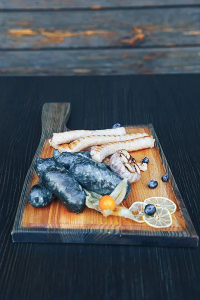 Embutidos negros fritos a la parrilla en una tabla de madera. Salchichas negras en la parrilla —  Fotos de Stock