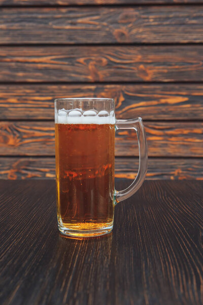 Close-up of a glass of beer on a wooden table. wooden background