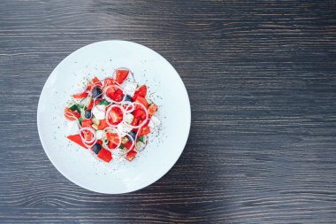 Beyaz tabakta sebze salatası. Beyaz bir plaka üzerinde geleneksel Yunan salatası. ahşap arka plan. üstten görünüm