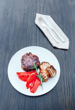 Izgara et beyaz tabakta patlıcan ve kırmızı biber ile. Beyaz tabakta sebzeli ızgara et. ahşap arka plan