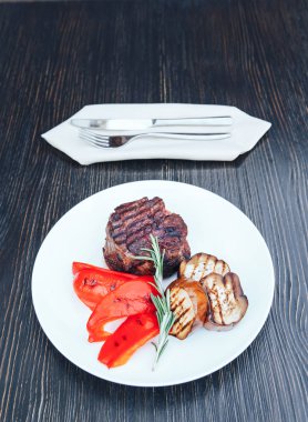 Izgara et beyaz tabakta patlıcan ve kırmızı biber ile. Beyaz tabakta sebzeli ızgara et. ahşap arka plan