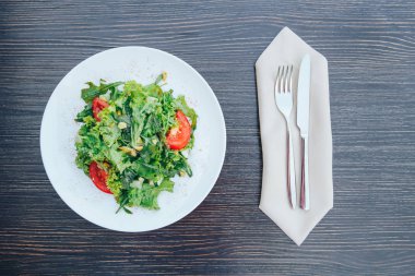 Salata Domates, roka, ayçekirdeği ve rustik ahşap arka plan üzerinde beyaz seramik plaka üzerinde otlar ile. Yaz salata domates, roka. üstten görünüm