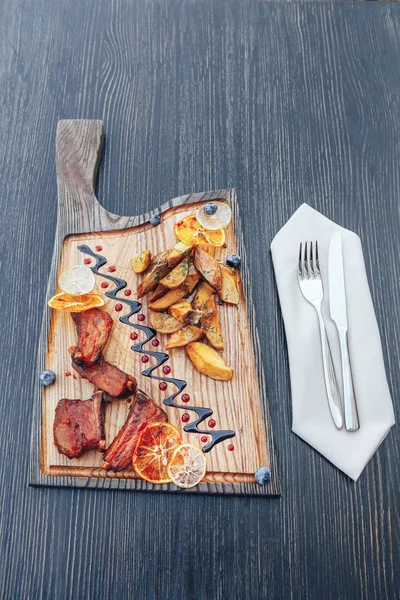 Fűszeres barbecue sertésborda hasábburgonyával, egy vágódeszka tálalva — Stock Fotó