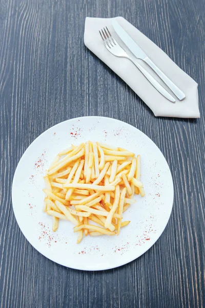 Franse frietjes op een witte plaat op een houten tafel — Stockfoto