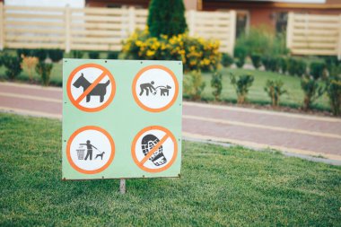 Yeşil bir bahçe içinde yasak işareti. Çöp atmayın, çimler üzerinde köpekler izin verilmez yürüyüş yapmak