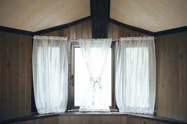 Деревянная стена и окно с занавесками. Старое деревянное окно с белыми занавесками — стоковое фото