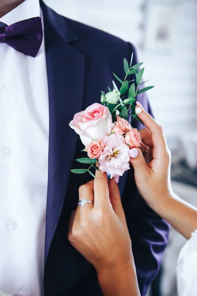 Noiva põe o noivo no boutonniere da rosa no dia do casamento — Fotografia de Stock