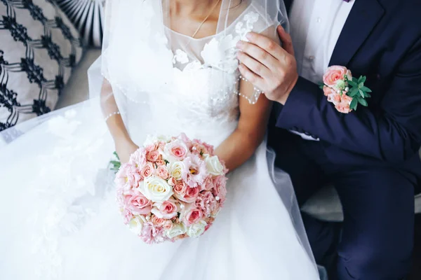 Mariée tient un bouquet de mariage dans les mains, le marié serre sa mariée ensemble. Concept amoureux de mariage. Gros plan — Photo