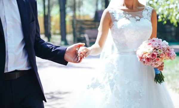 Elegante noivo e noiva com buquê de casamento de mãos dadas. Casamento casal — Fotografia de Stock