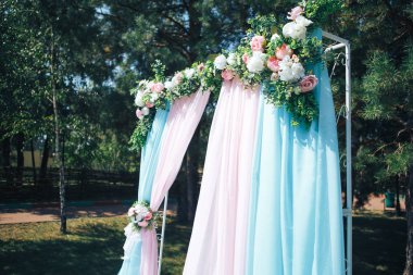 Düğün töreni açık havada. Düğün kemer çiçek dekore edilmiştir.