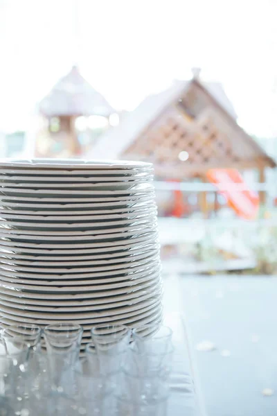 Стопка белой керамической тарелки на улице. сложенные белые блюда на столе — стоковое фото