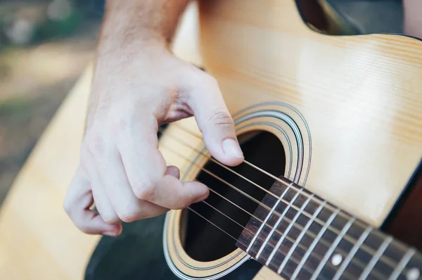 Primer plano del hombre tocando la guitarra. Hombre tocando la guitarra. Tocar en la guitarra acústica al aire libre — Foto de Stock
