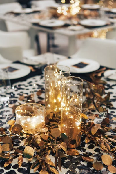 Diner tableis ingericht in zwart en goud. Garland in een maatkolf van glas. Huwelijksdecoratie — Stockfoto