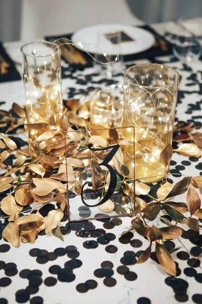 Il tavolo da pranzo è decorato in nero e oro. Ghirlanda in fiaschetta di vetro — Foto Stock