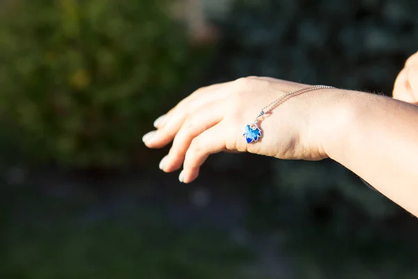 La mano femenina sostiene un collar azul. Decoración de esmalte — Foto de Stock