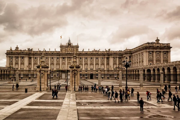 Madrid 'in Kraliyet Sarayı. İspanya, Avrupa baharda bulutlu bir gökyüzü. Sarayı ziyaret eden turistler, sokaklarda yürüyen insanlar..