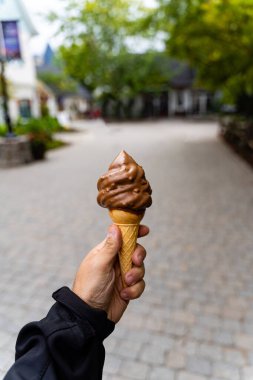 Elinde çikolatalı dondurma külahı tutan bir adam. Geçmişi çok bulanık, tarlanın derinliği çok az. Koyu arkaplan.