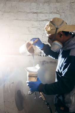 Müteahhit ayna çerçevesini boyamadan önce boyayı karıştırıyor.