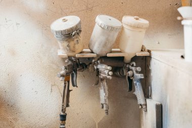 Marangozhane boyacısının manzarası. Duvarda asılı üç sprey tabanca var.