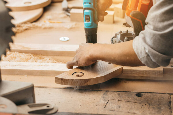 Carpenter drills a hole with an electrical drill