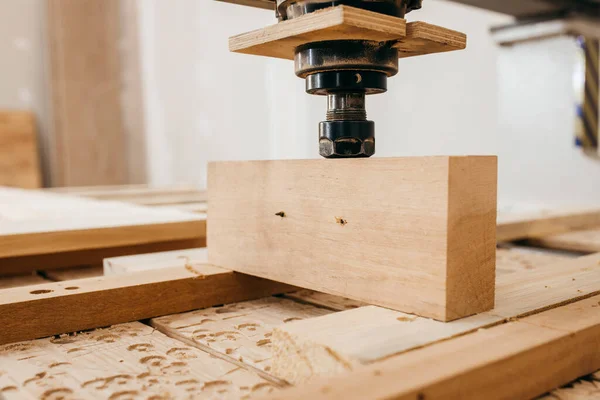 Close-up of cutting wood on a CNC milling machine in garage