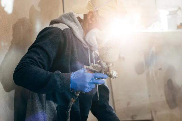 Master painter in a factory, industrial painting  wood with spray gun.