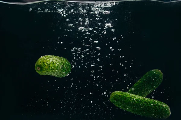 黒い背景の水に緑のキュウリ — ストック写真