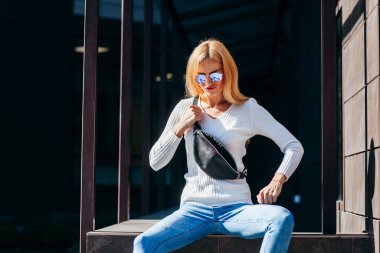 Şehirde gözlüklü, bel çantalı şık bir kız.