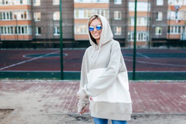 Gri kapüşonlu güzel, genç bir kızın açık hava fotoğrafı.