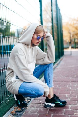 Gri kapüşonlu güzel, genç bir kızın açık hava fotoğrafı.