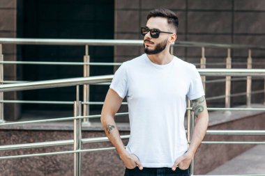 Beyaz tişörtlü ve gözlüklü, sakallı, şık bir genç. Sokak fotoğrafı