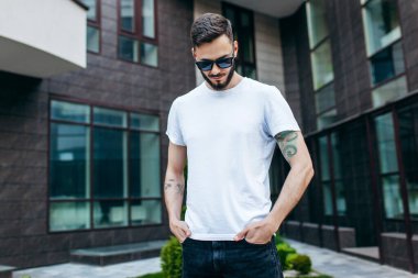 Beyaz tişörtlü ve gözlüklü, sakallı, şık bir genç. Sokak fotoğrafı