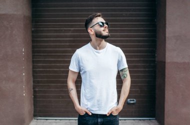 Beyaz tişörtlü ve gözlüklü, sakallı, şık bir genç. Sokak fotoğrafı