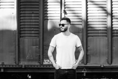 Beyaz tişörtlü ve gözlüklü, sakallı, şık bir genç. Sokak fotoğrafı