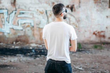 Sokakta duran, beyaz, boş tişört giyen genç adam. Sokak fotoğrafı. Yüzü yok